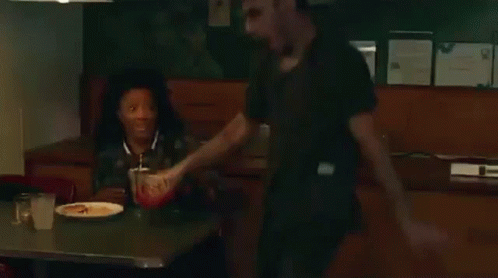 A Man And A Woman Are Sitting At A Table In A Diner Eating Food . GIF