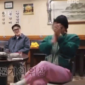 A Man And A Woman Are Sitting At A Table In A Restaurant With Chinese Writing On The Wall . GIF