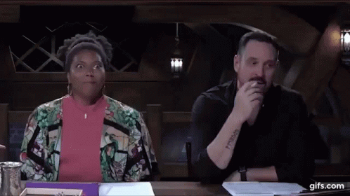 A Man And A Woman Are Sitting At A Table . The Woman Is Making A Funny Face . GIF