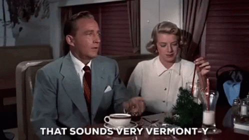 A Man And A Woman Are Sitting At A Table With A Cup Of Coffee And The Words That Sounds Very Vermont-Y GIF