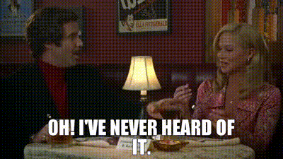 A Man And A Woman Are Sitting At A Table With A Lamp . GIF