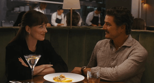 a man and a woman are sitting at a table with a martini