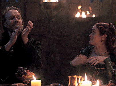 a man and a woman are sitting at a table with candles and a fire in the background