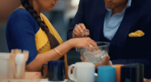 a man and a woman are sitting at a table with cups on it