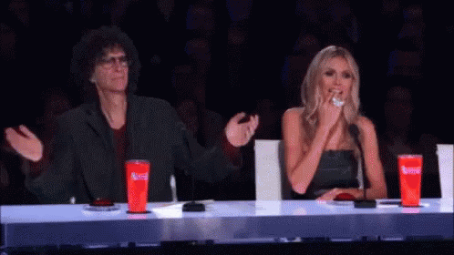 A Man And A Woman Are Sitting At A Table With Red Cups That Say Coca Cola On Them . GIF