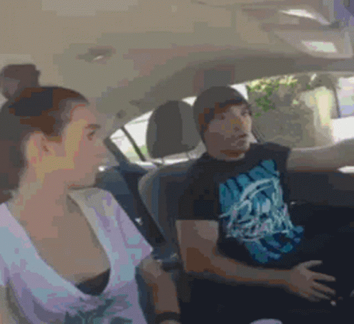A Man And A Woman Are Sitting In A Car And The Man Is Wearing A T-Shirt With A Skull On It GIF