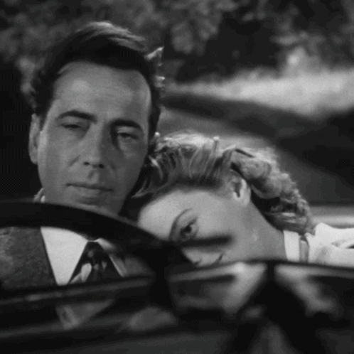 a man and a woman are sitting in a car and the woman is resting her head on the man 's steering wheel