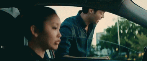 A Man And A Woman Are Sitting In A Car . The Woman Is Looking Out The Window . GIF