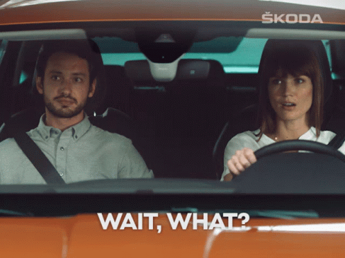A Man And A Woman Are Sitting In A Car With The Words Wait What On The Bottom GIF