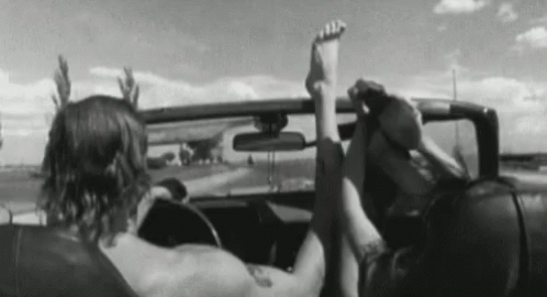 a man and a woman are sitting in a car with their feet up in the air .