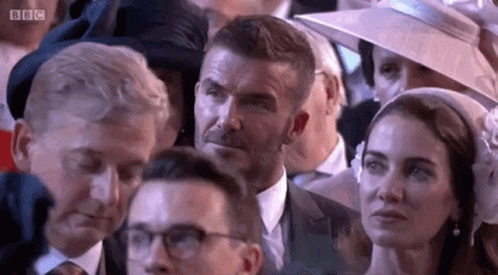 a man and a woman are sitting in a crowd of people .