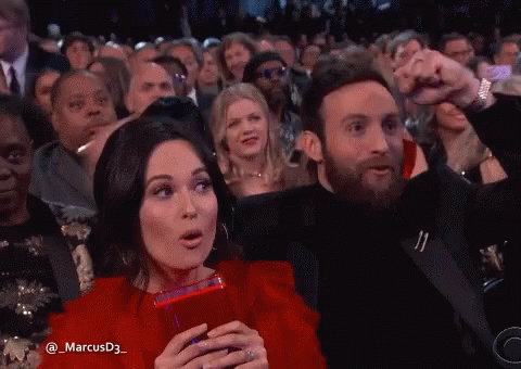 A Man And A Woman Are Sitting In A Crowd With The Name Marcusd3 On The Bottom GIF