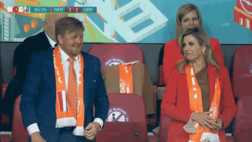 a man and a woman are sitting in a stadium watching a game .