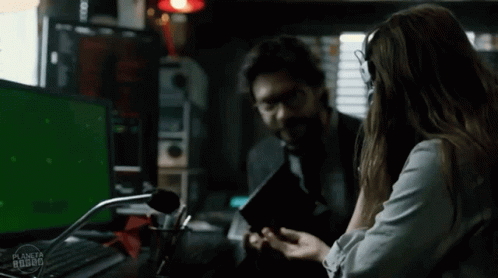 A Man And A Woman Are Sitting In Front Of A Green Screen With The Word Planeta On It GIF