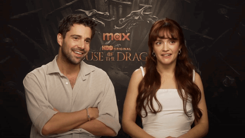 A Man And A Woman Are Sitting In Front Of A Poster For Max Hbo Original House Of The Dragon GIF