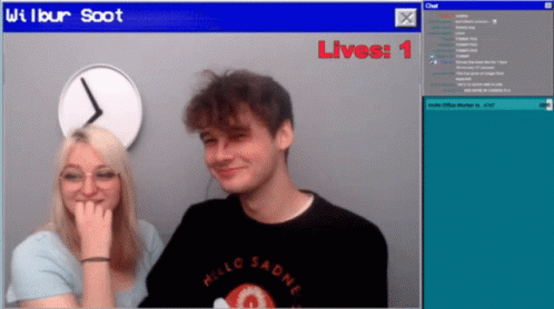 A Man And A Woman Are Sitting In Front Of A Screen That Says Wilbur Soot Lives 1 GIF