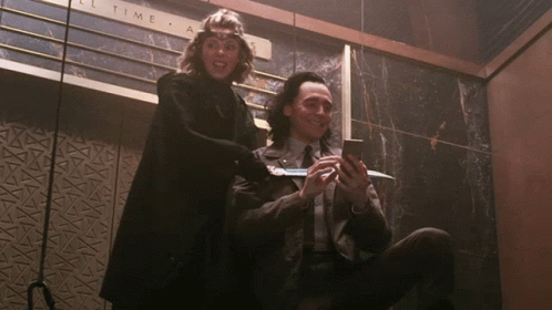 A Man And A Woman Are Sitting In Front Of A Sign That Says " All Time " GIF