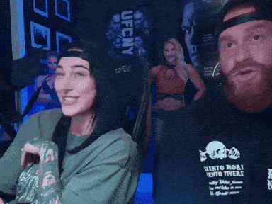 A Man And A Woman Are Sitting In Front Of A Sign That Says Ufc Ny GIF