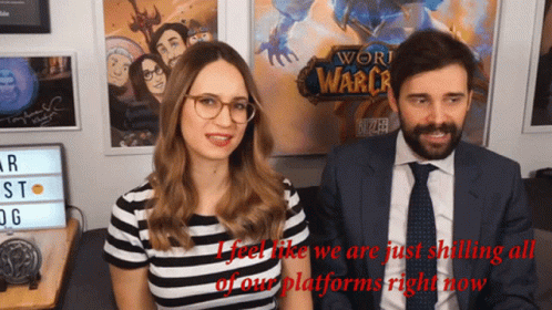 A Man And A Woman Are Sitting In Front Of A Sign That Says World Of Warcraft GIF