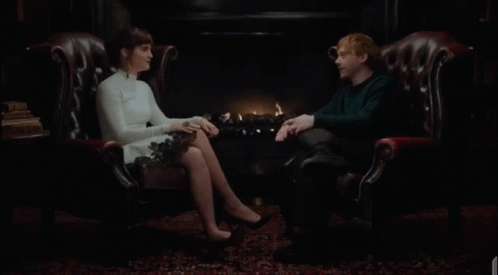 a man and a woman are sitting in leather chairs laughing