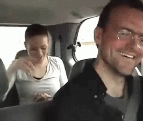 A Man And A Woman Are Sitting In The Back Of A Car . GIF