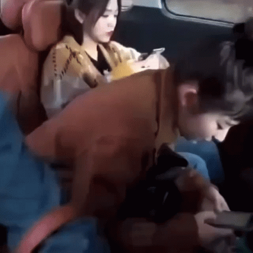 A Man And A Woman Are Sitting In The Back Seat Of A Car . GIF