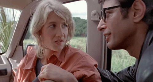 A Man And A Woman Are Sitting In The Back Seat Of A Car Talking To Each Other . GIF