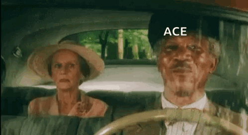 A Man And A Woman Are Sitting In The Back Seat Of A Car . The Man Is Wearing A Hat And Bow Tie . GIF