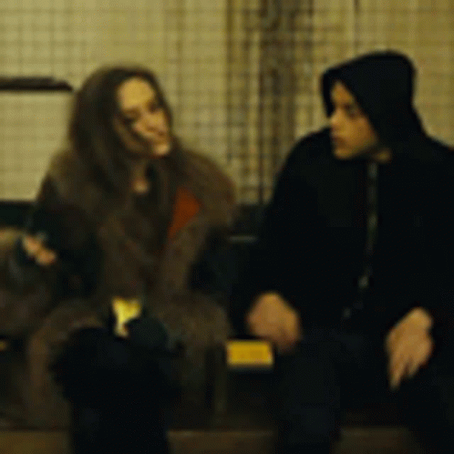 A Man And A Woman Are Sitting Next To Each Other And Talking . GIF