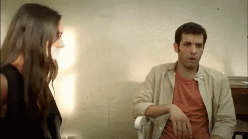 A Man And A Woman Are Sitting Next To Each Other And Talking To Each Other . GIF