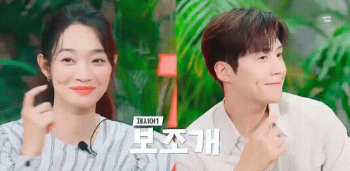 A Man And A Woman Are Sitting Next To Each Other And The Woman Is Smiling . GIF