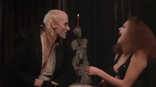 A Man And A Woman Are Sitting Next To Each Other In A Dark Room . The Woman Is Screaming At The Man . GIF