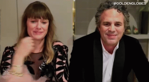 A Man And A Woman Are Sitting Next To Each Other In A Room . The Woman Is Crying And The Man Is Smiling . GIF