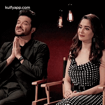A Man And A Woman Are Sitting Next To Each Other In Chairs . GIF