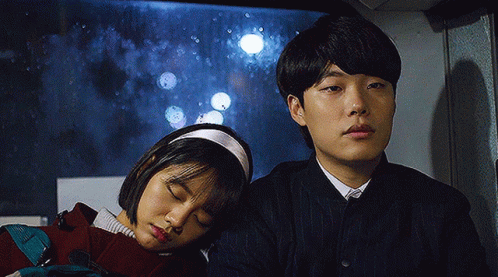 A Man And A Woman Are Sitting Next To Each Other On A Bus With Their Eyes Closed . GIF