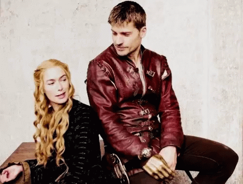A Man And A Woman Are Sitting Next To Each Other On A Table . The Man Is Wearing A Red Leather Jacket . GIF