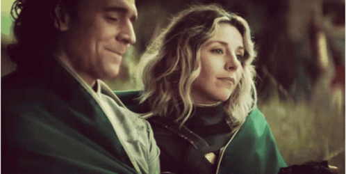 A Man And A Woman Are Sitting Next To Each Other . GIF
