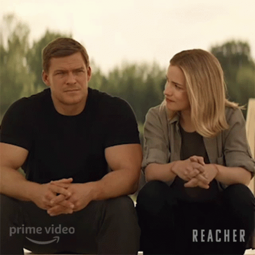 A Man And A Woman Are Sitting Next To Each Other With The Word Reacher On The Bottom Right GIF