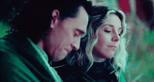 A Man And A Woman Are Sitting Next To Each Other With Their Heads Together . GIF