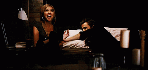 A Man And A Woman Are Sitting On A Bed And The Woman Is Screaming GIF