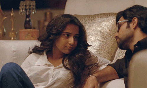 A Man And A Woman Are Sitting On A Couch GIF