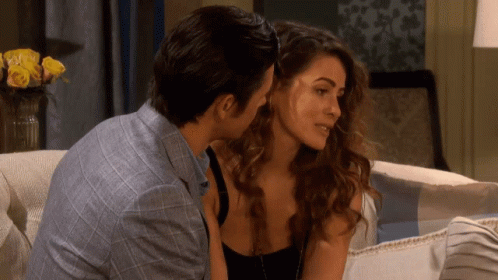 A Man And A Woman Are Sitting On A Couch And Kissing GIF