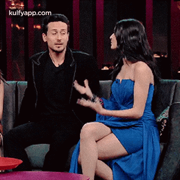 A Man And A Woman Are Sitting On A Couch And Talking . The Woman Is Wearing A Blue Dress . GIF