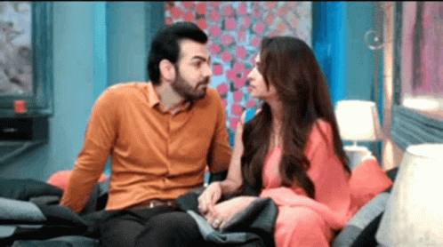 A Man And A Woman Are Sitting On A Couch And Talking To Each Other . GIF
