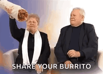 A Man And A Woman Are Sitting On A Couch And The Woman Is Holding A Large Burrito . GIF