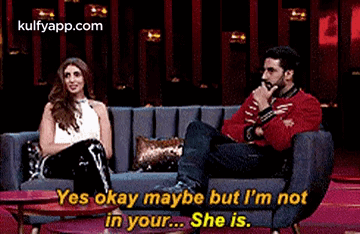 A Man And A Woman Are Sitting On A Couch . GIF