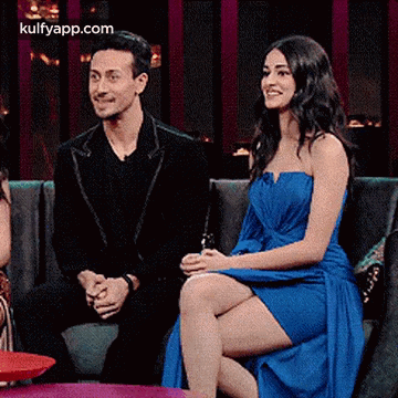 A Man And A Woman Are Sitting On A Couch . GIF