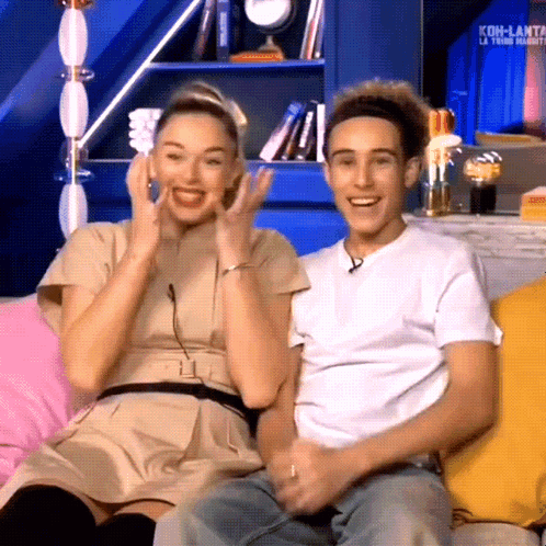 Man And Woman Sitting On Couch With Koh-Lanta Sign GIF