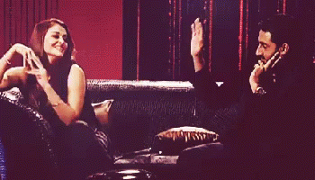 A Man And A Woman Are Sitting On A Couch With The Woman Dancing GIF