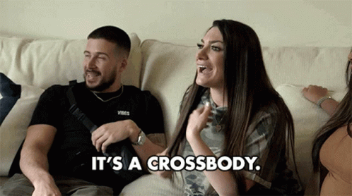 A Man And A Woman Are Sitting On A Couch With The Woman Saying It 'S A Crossbody . GIF
